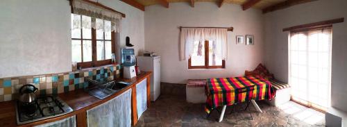 a kitchen with a sink and a refrigerator and a table at Rancho Quitapenas Bungalows in San Pedro de Atacama