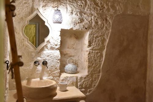 Baño de piedra con lavabo y espejo en Villa Amore Bianco, en Ostuni