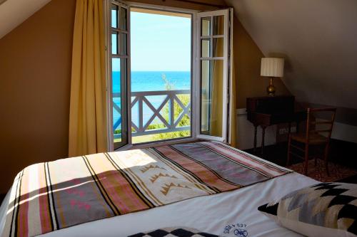 um quarto com uma grande janela com vista para o oceano em Chambres d'hôtes Les 4 Vents Pointe du Hoc - Landing Beaches em Grandcamp-Maisy