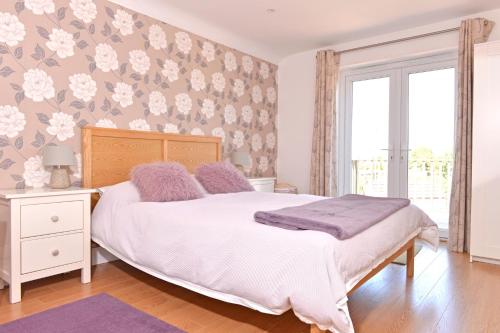a bedroom with a white bed and a floral wallpaper at Pevensey Beach Retreat in Pevensey