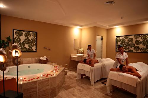 a spa room with two women in beds and a tub at Terrazas Apartments by Bahia Principe in Tulum