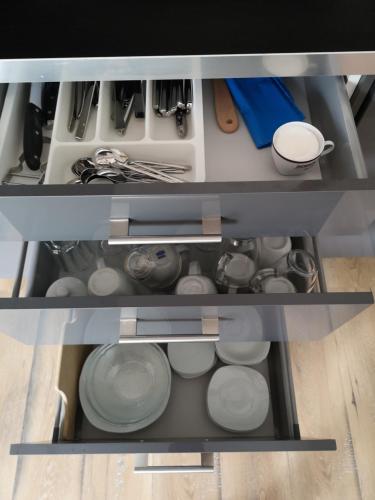 an open kitchen drawer with dishes and utensils at Agroturystyka u Karoliny in Sarbinowo