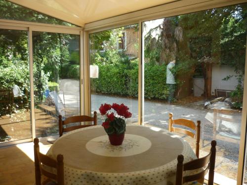 a table with a vase of flowers on it in front of a window at La villa des fleurs in Lamalou-les-Bains