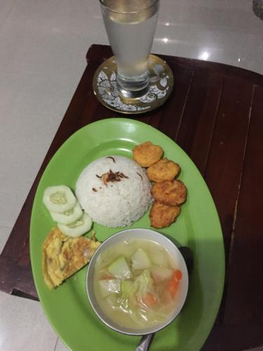 a green plate with rice and a bowl of food at Boneputeh Homestay in Taliwang