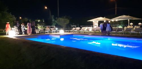 a swimming pool at night with people standing around it at Villa Savarino in Vittoria