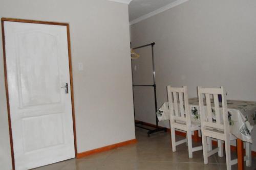 a room with a table and chairs and a white door at Garden Wing in Upington