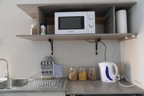 a kitchen counter with a microwave and a sink at Garden Wing in Upington