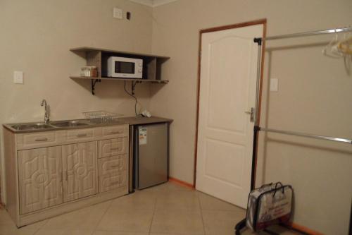 eine Küche mit einer Spüle und einer Mikrowelle in der Unterkunft Garden Wing in Upington