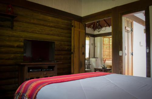 a bedroom with a bed and a flat screen tv at Pousada Rancho da Ferradura in Petrópolis