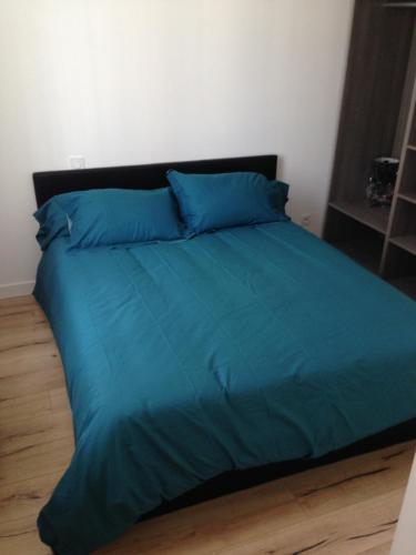 un letto con lenzuola blu e cuscini blu sopra di Joli appartement 40m2 entièrement équipé idéal pour location thermale ou saisonnier a Rochefort