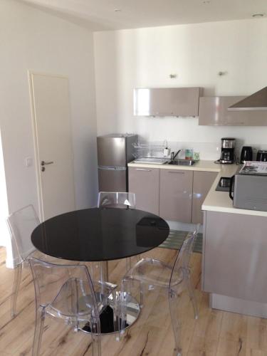 une cuisine avec une table noire et des chaises dans l'établissement Appartement 40m2 hyper centre avec fibre gratuite, à Rochefort
