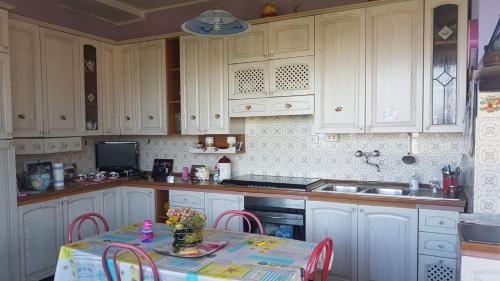 a kitchen with white cabinets and a table with chairs at Appartamento Panoramico in San Felice Circeo