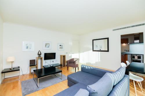 a living room with a blue couch and a kitchen at Horizon Canary Wharf Apartments in London