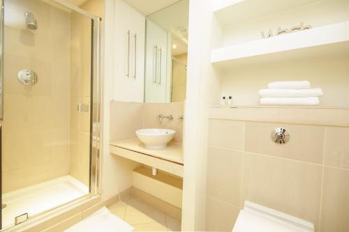 a white bathroom with a shower and a sink at Horizon Canary Wharf Apartments in London