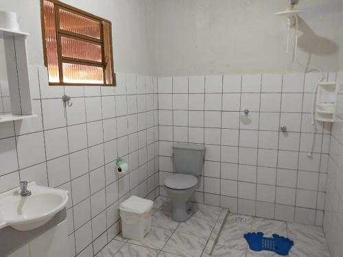 a white bathroom with a toilet and a sink at Pousada & Pesca Esportiva Fazolin in Socorro