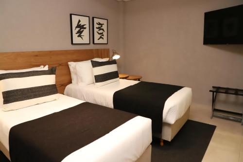 a hotel room with two beds and a flat screen tv at Agua del Corral Hotel & Spa in Mendoza
