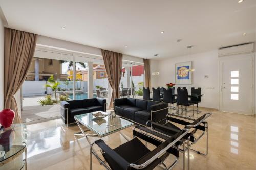 a living room with black chairs and a glass table at Villa Deluxe Suites Maspalomas in Maspalomas