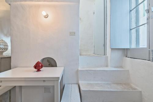 een witte kamer met een witte tafel en een trap bij Casa Le Mura in Ostuni