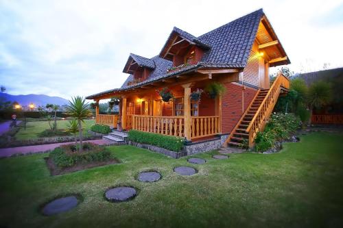 a large wooden house with a deck on a yard at Puertolago Country Inn & Resort in Otavalo