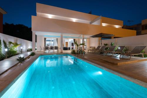 a villa with a swimming pool at night at Villa Deluxe Suites Maspalomas in Maspalomas