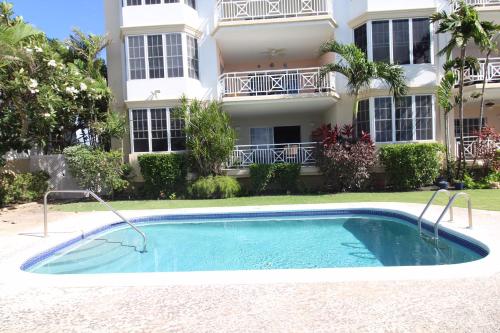 a swimming pool in front of a building at Beachfront Apartment in St. Lawrence Gap - Close To Your Every Need in Christ Church