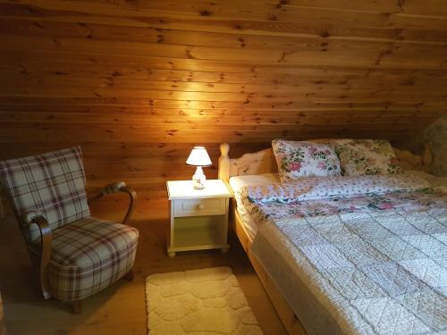 ein Schlafzimmer mit einem Bett und einem Stuhl in einer Hütte in der Unterkunft Wyspa Świerków in Lipusz