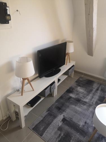 a living room with a tv on a table with two lamps at Cosy village in Bonneuil-en-France