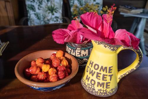 a vase and a bowl of fruit and flowers on a table at Pousada Aventurine Noronha in Fernando de Noronha