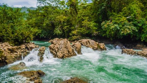 a waterfall on a river with rocks and trees at Ch'i Bocól Community Hostel in Lanquín