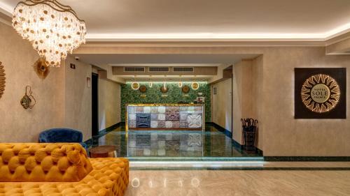 a lobby with a yellow couch and a chandelier at Sole Palace in Tbilisi City