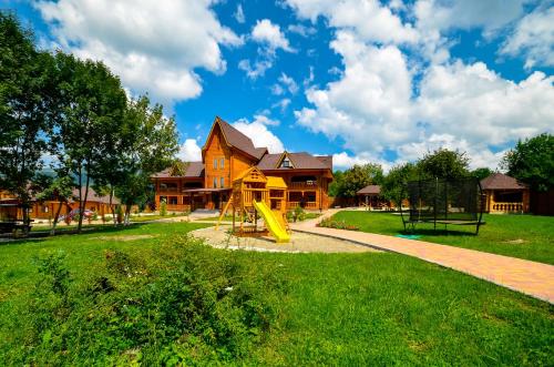 a playground in front of a house with a yellow slide at Boyarsky Dvor Inn in Dakhovskaya