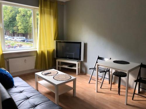 Vanalinna Apartment في تالين: غرفة معيشة مع أريكة وتلفزيون وطاولة