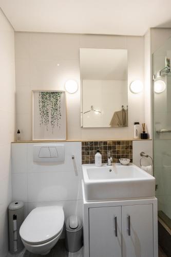 a bathroom with a sink and a toilet and a mirror at #1803 Cartwright - Simply Spectacular in Cape Town