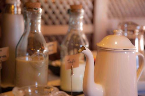una jarra blanca de leche y dos botellas de vidrio sobre una mesa en Hotel Rural Camero Viejo, en Laguna de Cameros