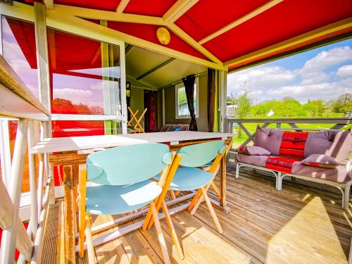 a porch with a table and chairs and a couch at Au Bonheur Nomade in Livry