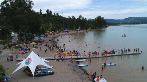 a group of people on a beach with a pier at Cabañas entre montañas in Rari