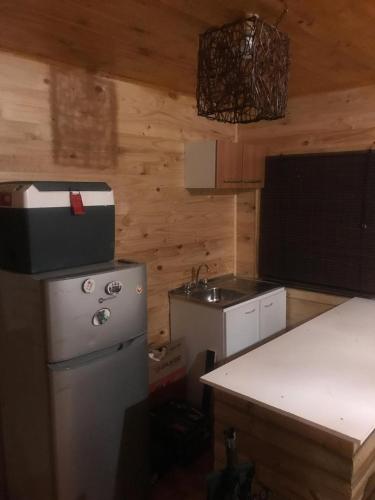 a kitchen with a stove and a sink and a refrigerator at Cabañas entre montañas in Rari