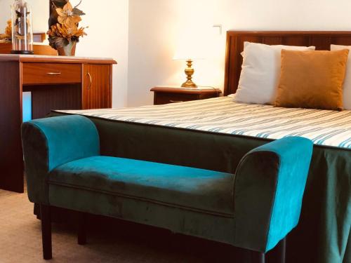 um quarto com uma cama com um banco de pés azul em Hospedaria S. Jorge em Fátima