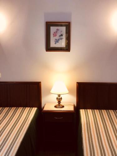 a bedroom with two beds and a lamp on a night stand at Hospedaria S. Jorge in Fátima