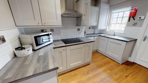 a kitchen with white cabinets and a sink and a microwave at Bishop's Gate Hotel in Derry Londonderry