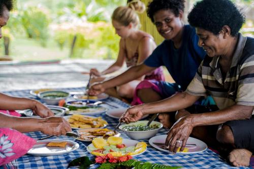 Namosi Eco Retreat في Navunikambi: مجموعة من الناس يجلسون حول طاولة يأكلون الطعام