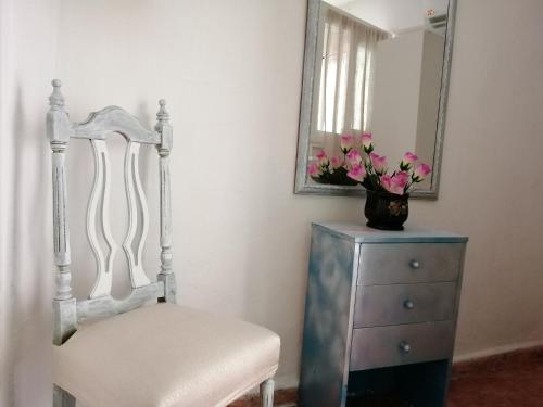 a chair and a dresser with a mirror and flowers at H Juan in Marbella