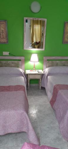 a green room with two beds and a table with a lamp at H Juan in Marbella