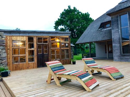 two chairs on a wooden deck with a building at Pūjalgi in Ēdole