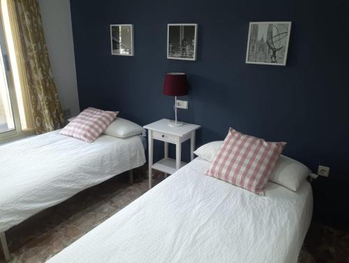 ein Schlafzimmer mit zwei Betten und einem Tisch mit Lampe in der Unterkunft Piso muy amplio Casco Historico in Cartagena