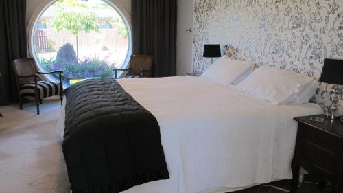 a bedroom with a large white bed with a window at Kerry Lodge Bed & Breakfast in Napier