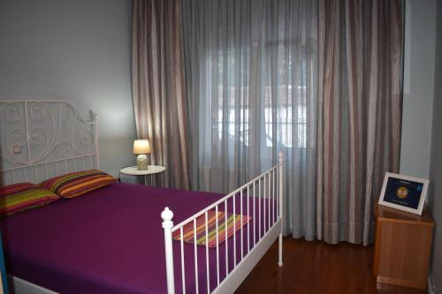 a bedroom with a purple bed and a window at Enipeas Apartment in Litochoro