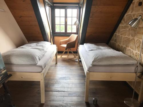 2 camas en una habitación con mesa y silla en Fewo TURMZIMMER im Rittergut Leppersdorf bei Dresden, en Leppersdorf