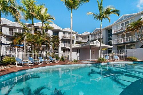 a swimming pool with palm trees in front of a building at Champelli Palms Apartments in Gold Coast