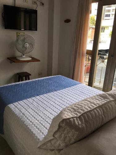 a bedroom with a bed with a fan and a window at Hotel Armont in Calarcá